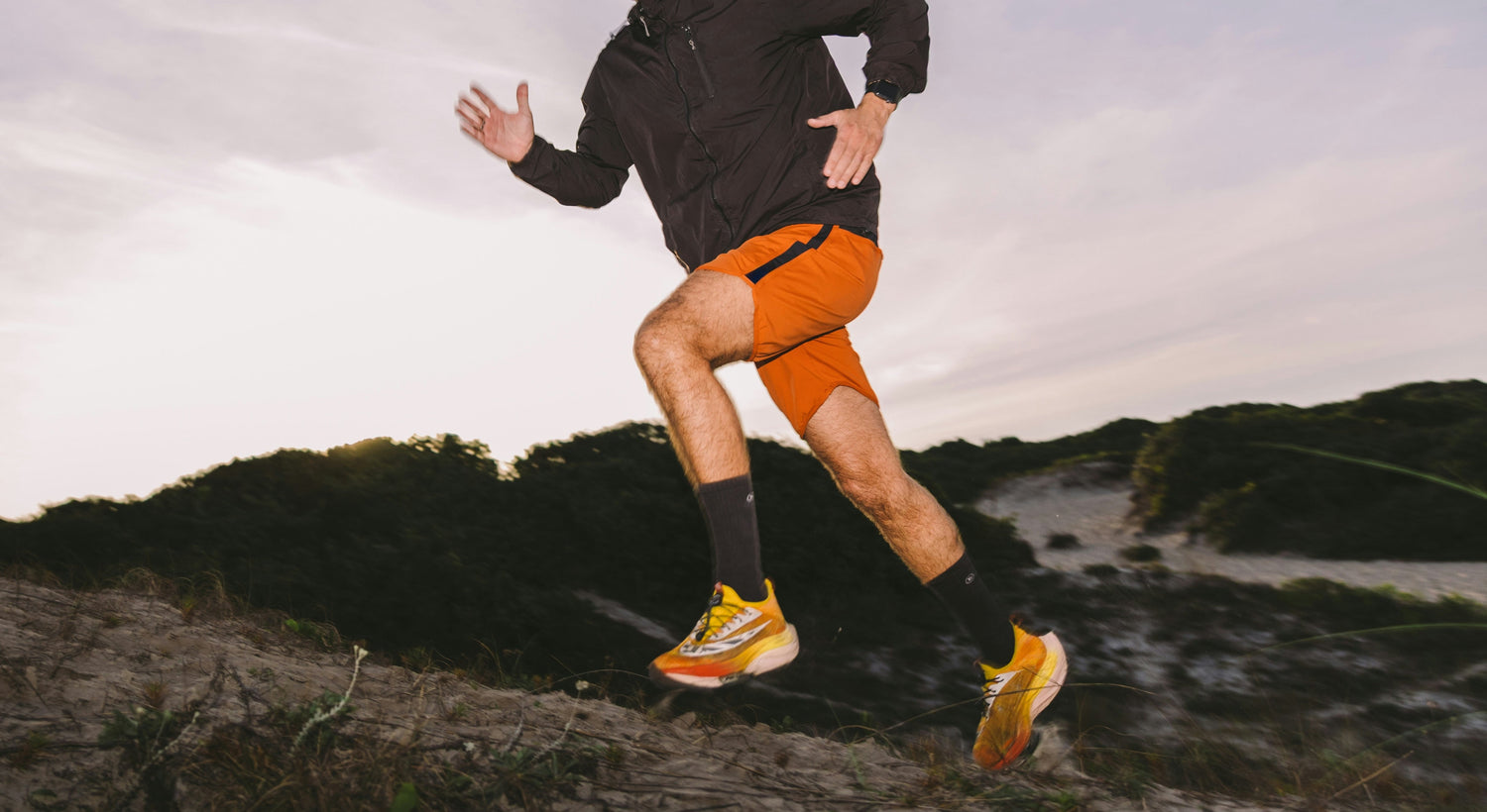 Sportif portant un short orange en train de courir sur des dunes